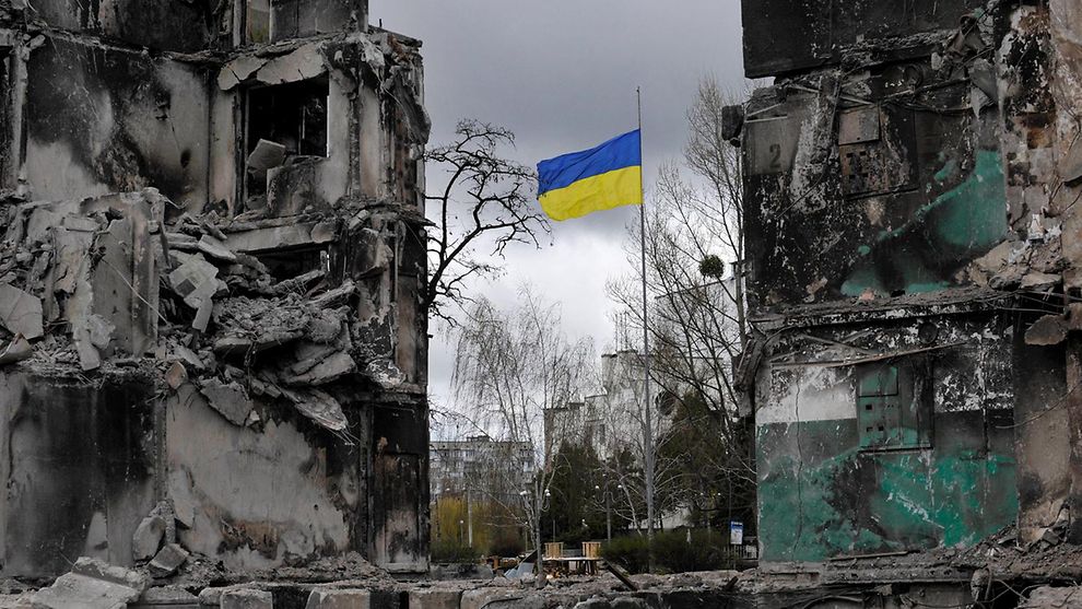 Zerstörte Gebäude in der Ukraine mit ukrainischer Fahne im Hintergrund