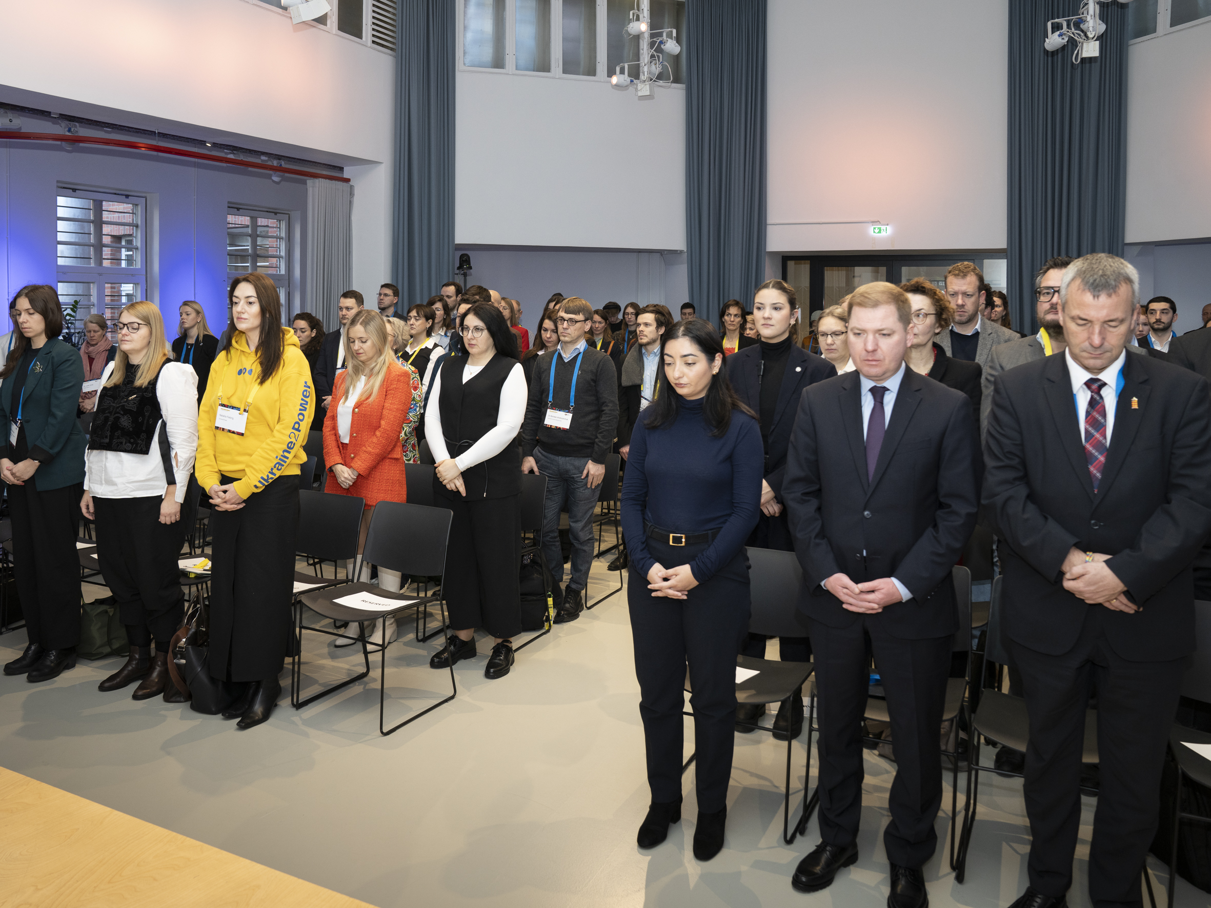 Foto von mehreren Menschen, die in Reihen in einem Raum stehen.