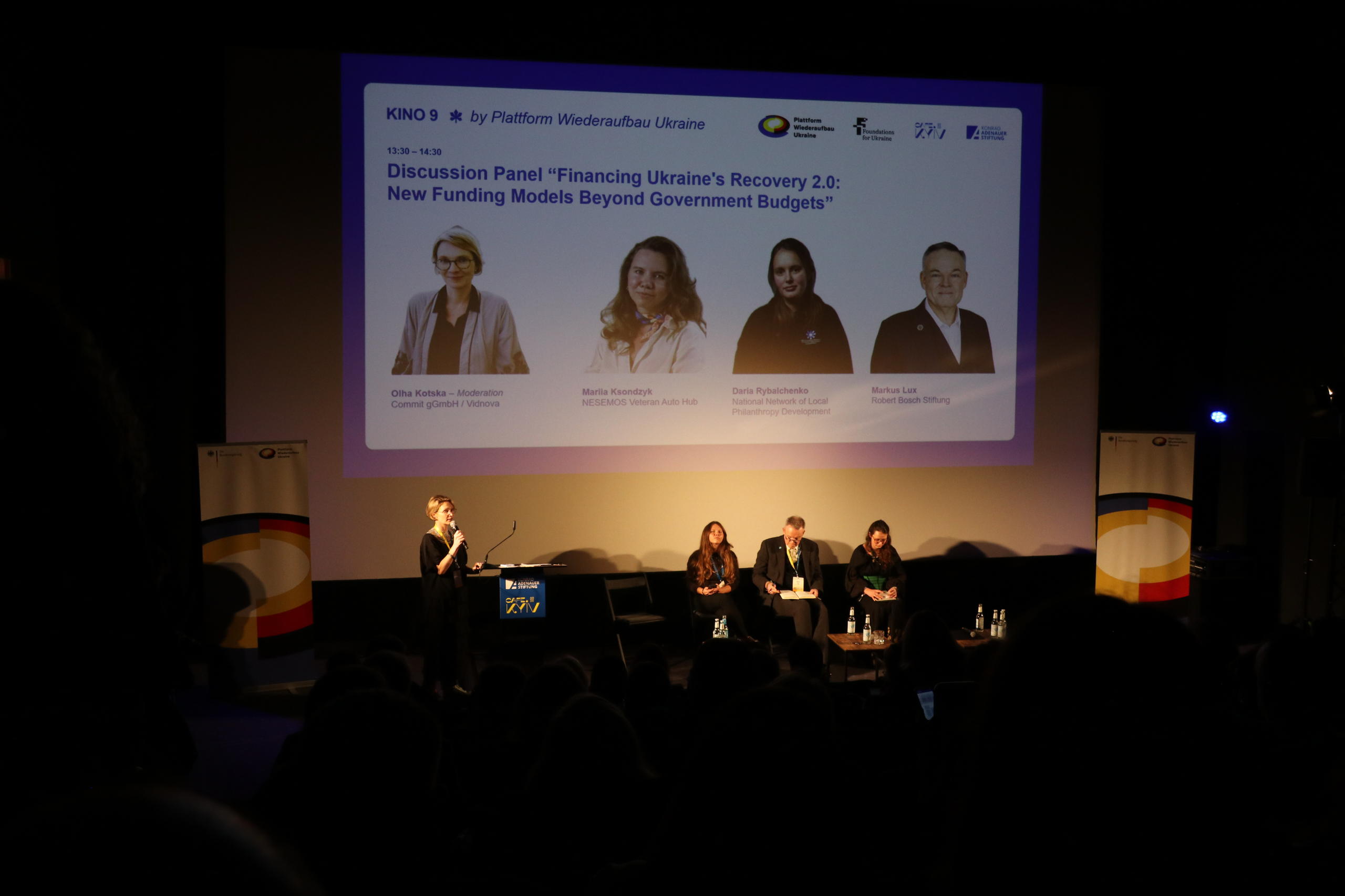 Foto von einem Panel mit vier Menschen und einer Präsentation im Hintergrund.