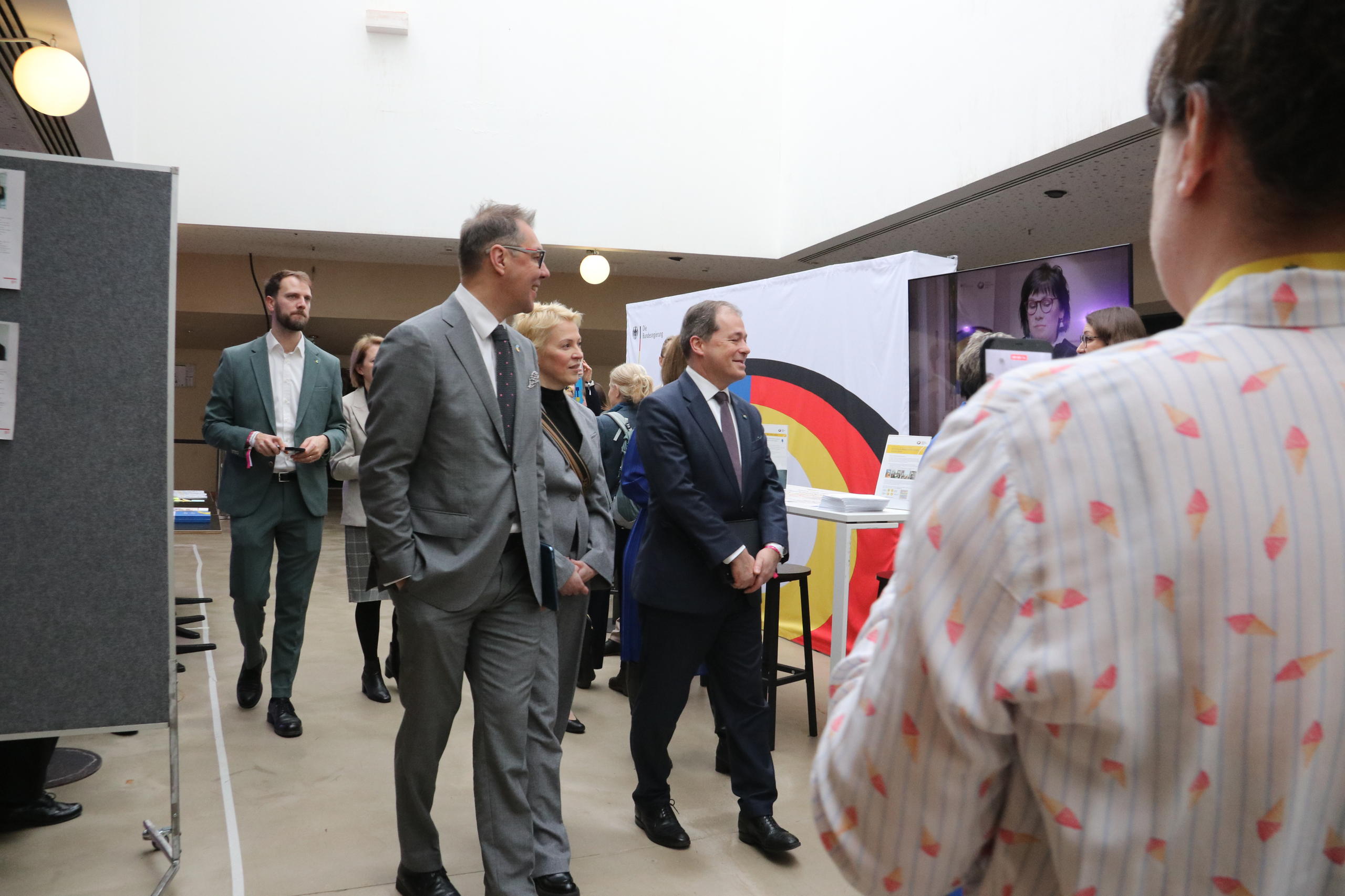 Foto von einem Messestand, an dem Menschen vorbeigehen.